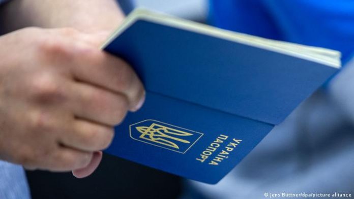 A man's hand holds a Ukrainian passport